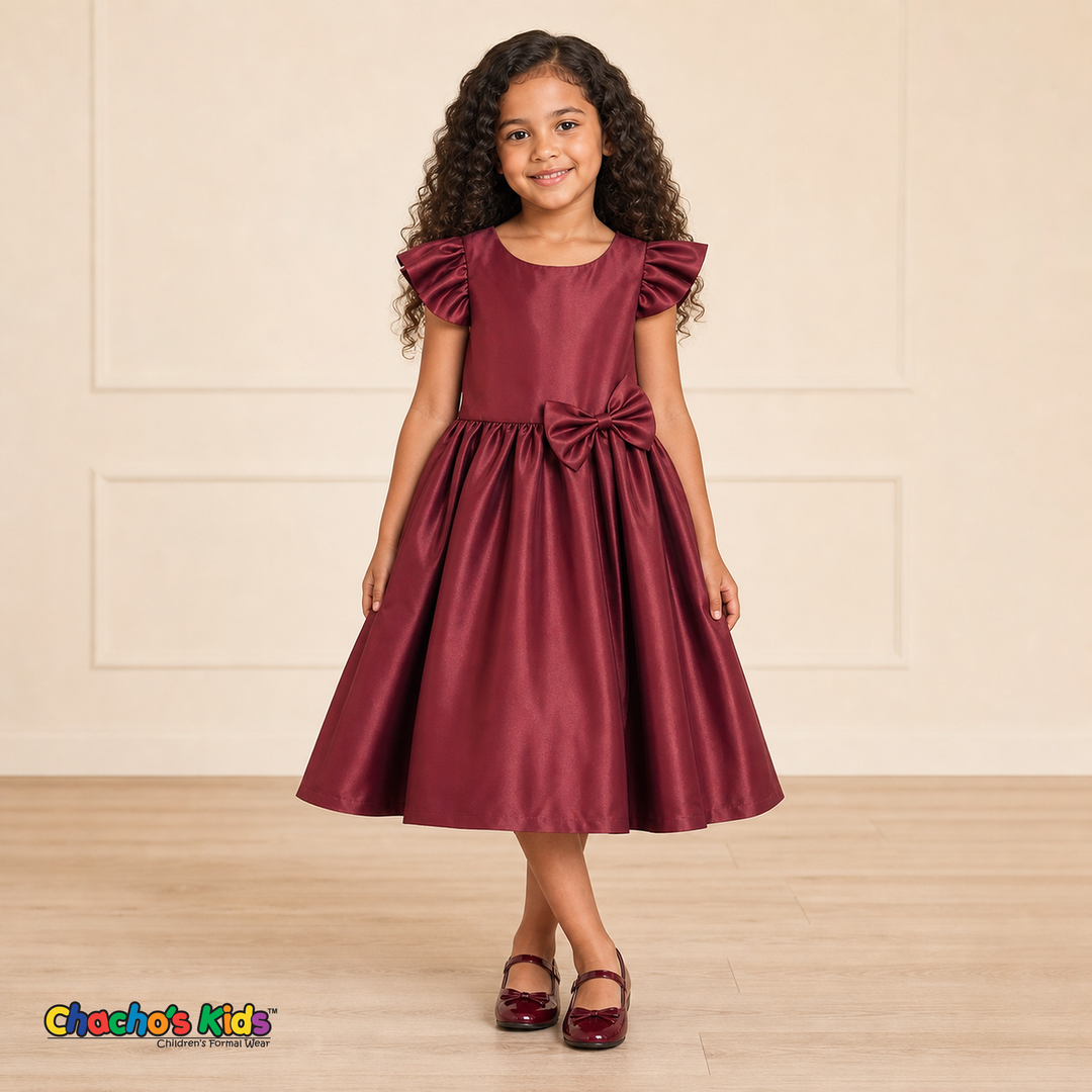 Girl wearing burgundy satin flower girl dress with bow, flutter sleeves and full skirt