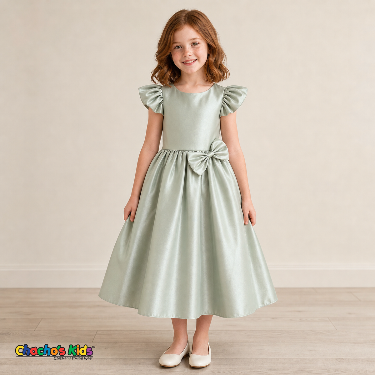 Girl wearing sage green satin flower girl dress with bow, flutter sleeves and full skirt