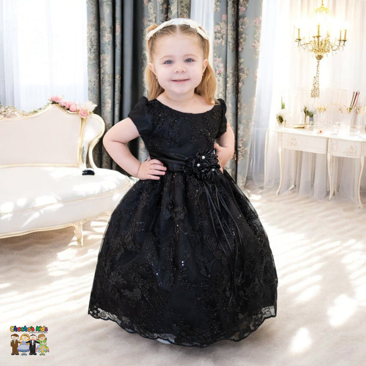 Girl wearing black embroidered flower girl dress with satin bow, cap sleeves and full tulle skirt