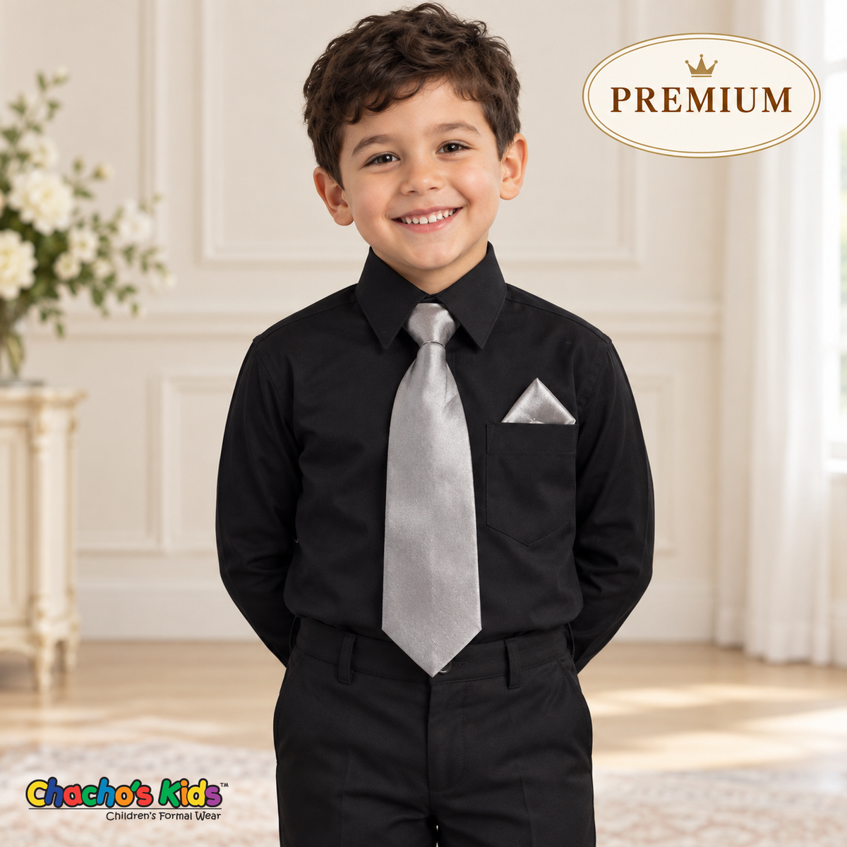 Boy wearing a premium black dress shirt tucked into dress pants, with a silver satin tie and triangular silver pocket square.