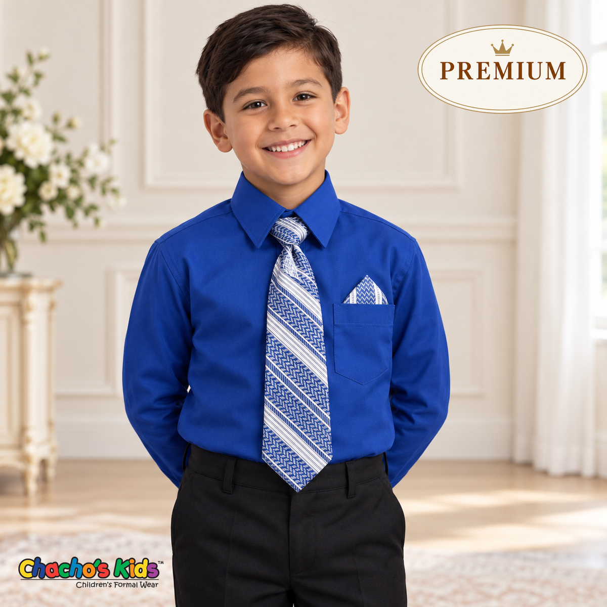 Boy wearing a premium royal blue dress shirt with a blue-and-white patterned tie and triangular pocket square, tucked into black dress pants.